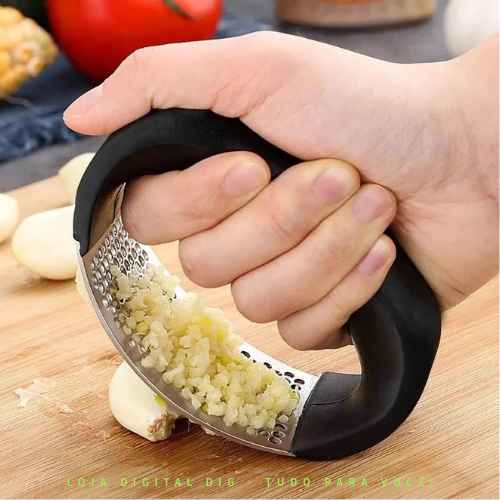 Na imagem: Pessoa utilizando o espremedor de alho estiloso em inox! Com cabo ergonômico! Design que se encaixa na pegada da mão para facilitar e espremer o alho de forma mais efetiva. Adquira o seu agora mesmo na Loja Digital DIG! LDDIG!